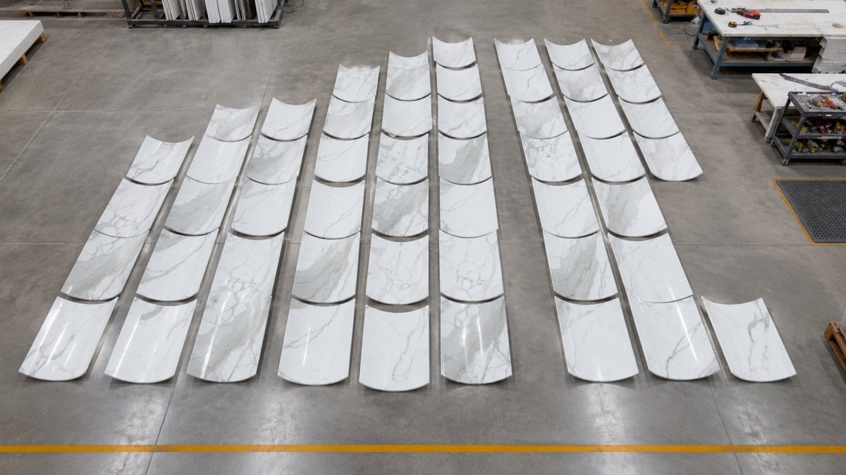 Factory pre-layout of curved white marble-look stone wall panels before project installation